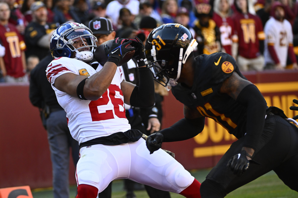 New York Giants running back Saquon Barkley (26) catches a touchdown past Washington Commanders safety Kamren Curl (31) during the first half at FedExField.
